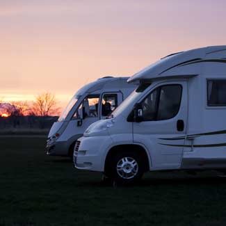 side view of two recreational vehicles parked in a field