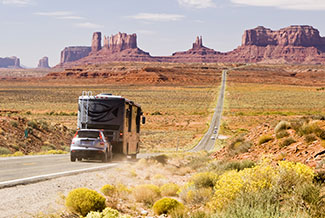 recreational vehicle towing a small car through the desert